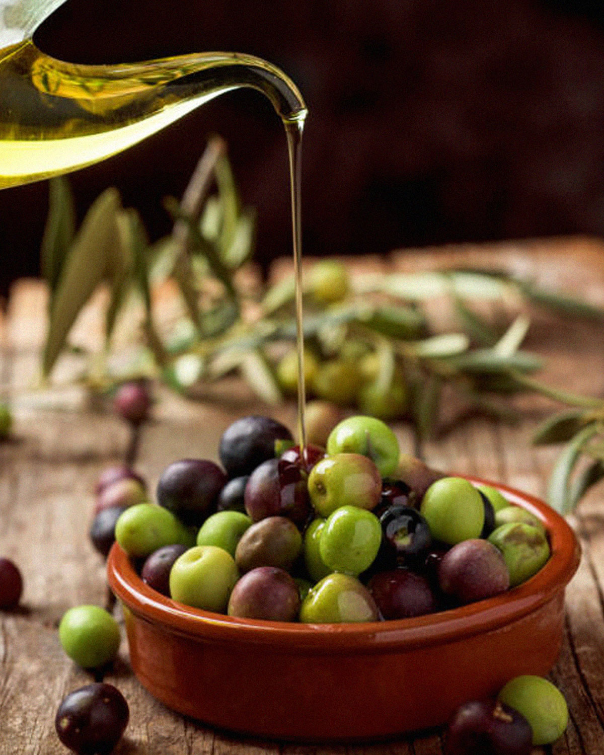 pouring olive oil on top of olives in a small bowl