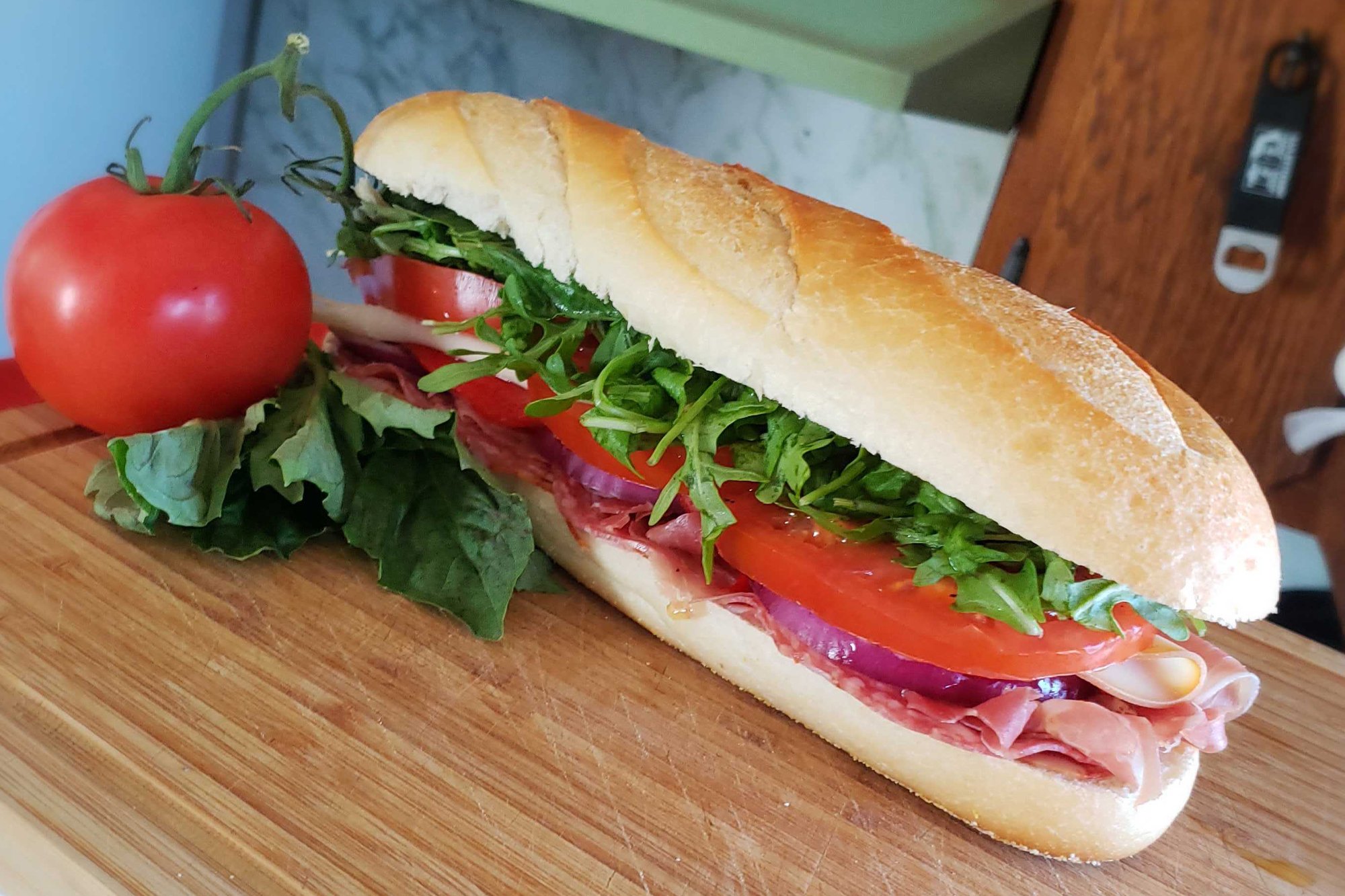 Close up of Super Italian Sub on cutting board with full tomato