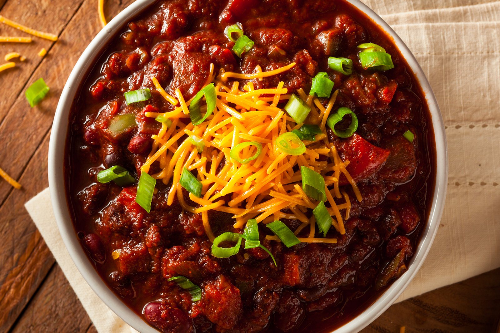 Overhead shot of chili in a bowl with green onions and cheese on top