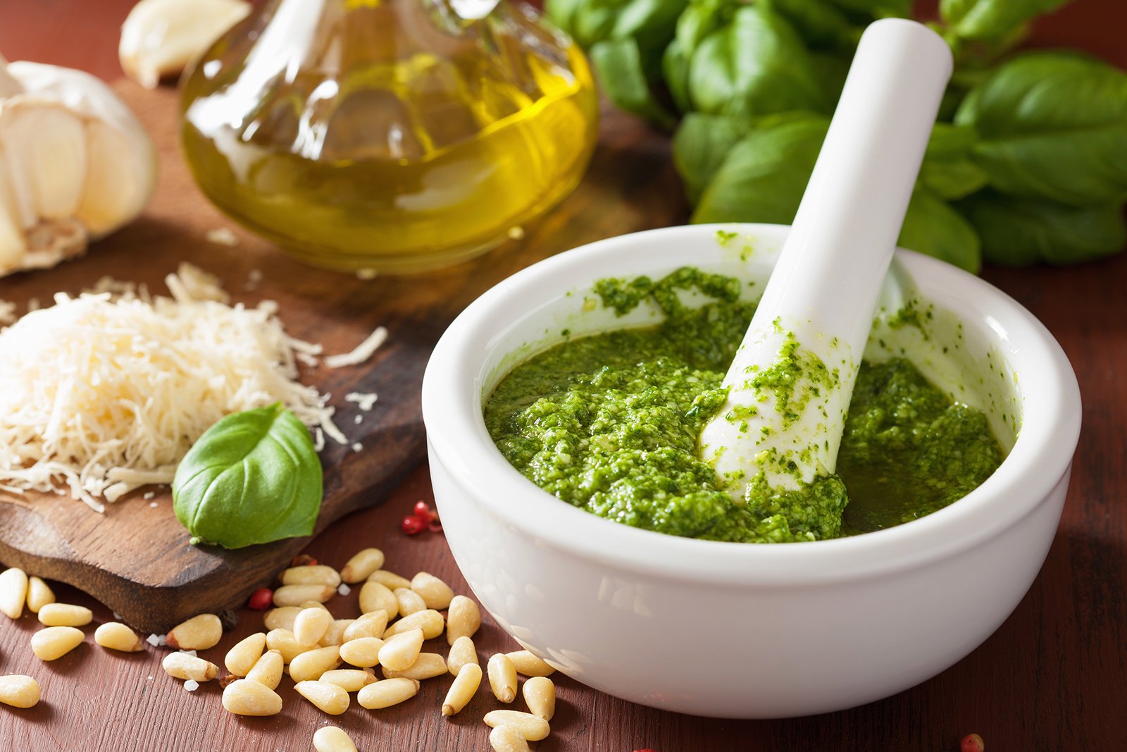 Cooking table with olive oil, cheese and a fresh bowl of pesto sauce