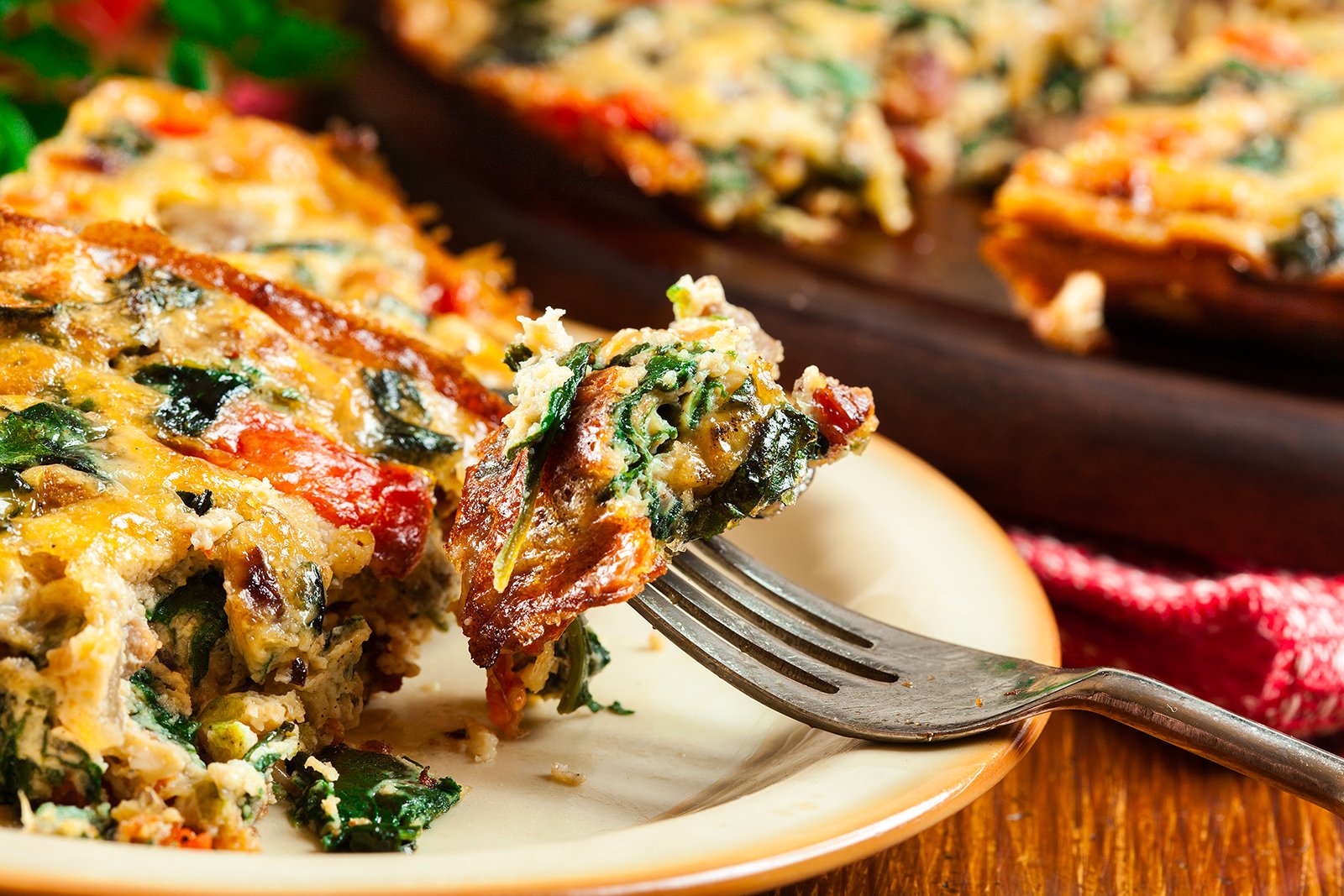 Frittata with eggs, spinach and mushrooms on plate with fork
