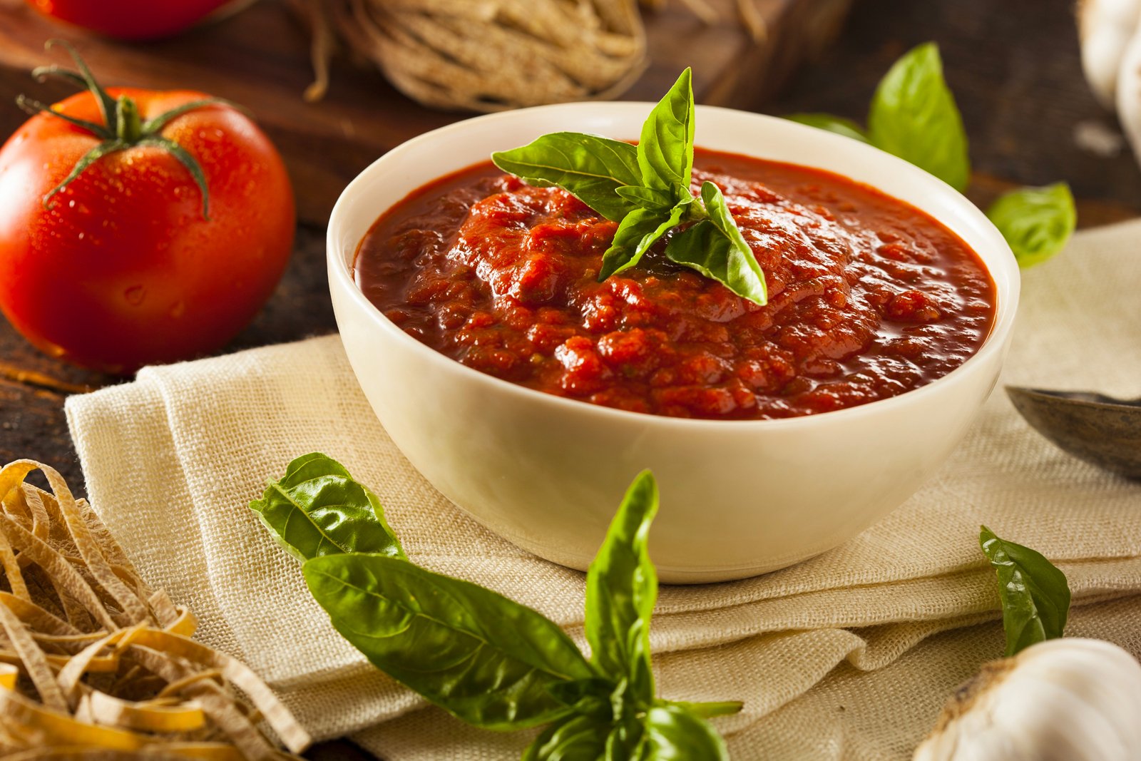 Homemade marinara sauce in a bowl with basil around it