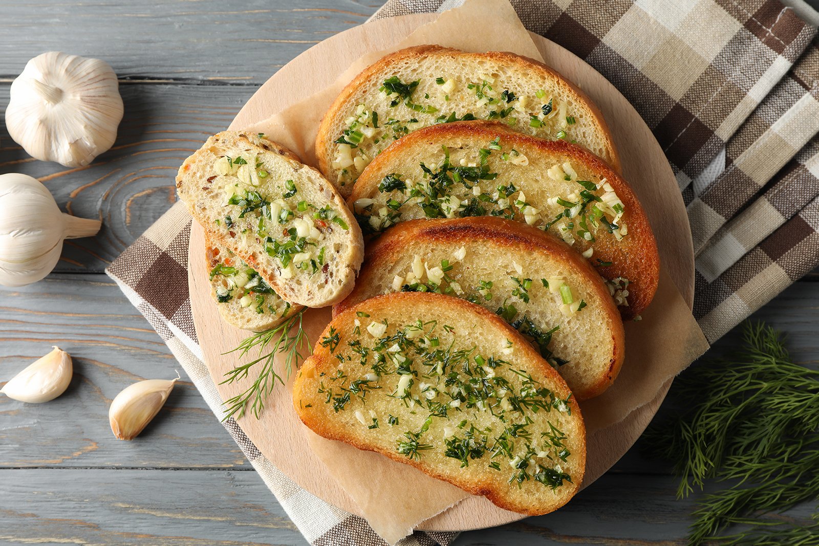Overhead view of garlic bread with garlic cloves surrounding 