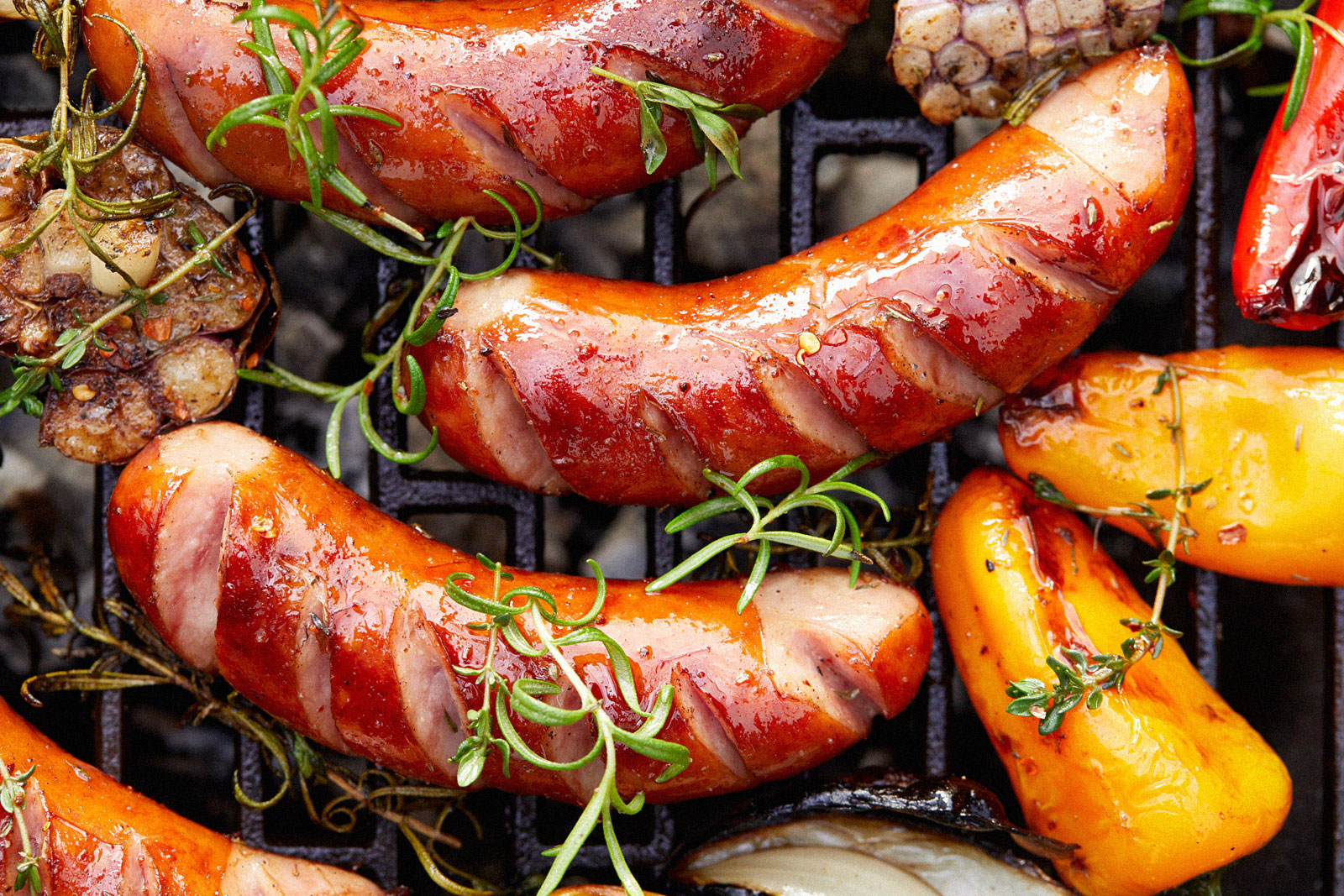 sausages and peppers cooking on a grill