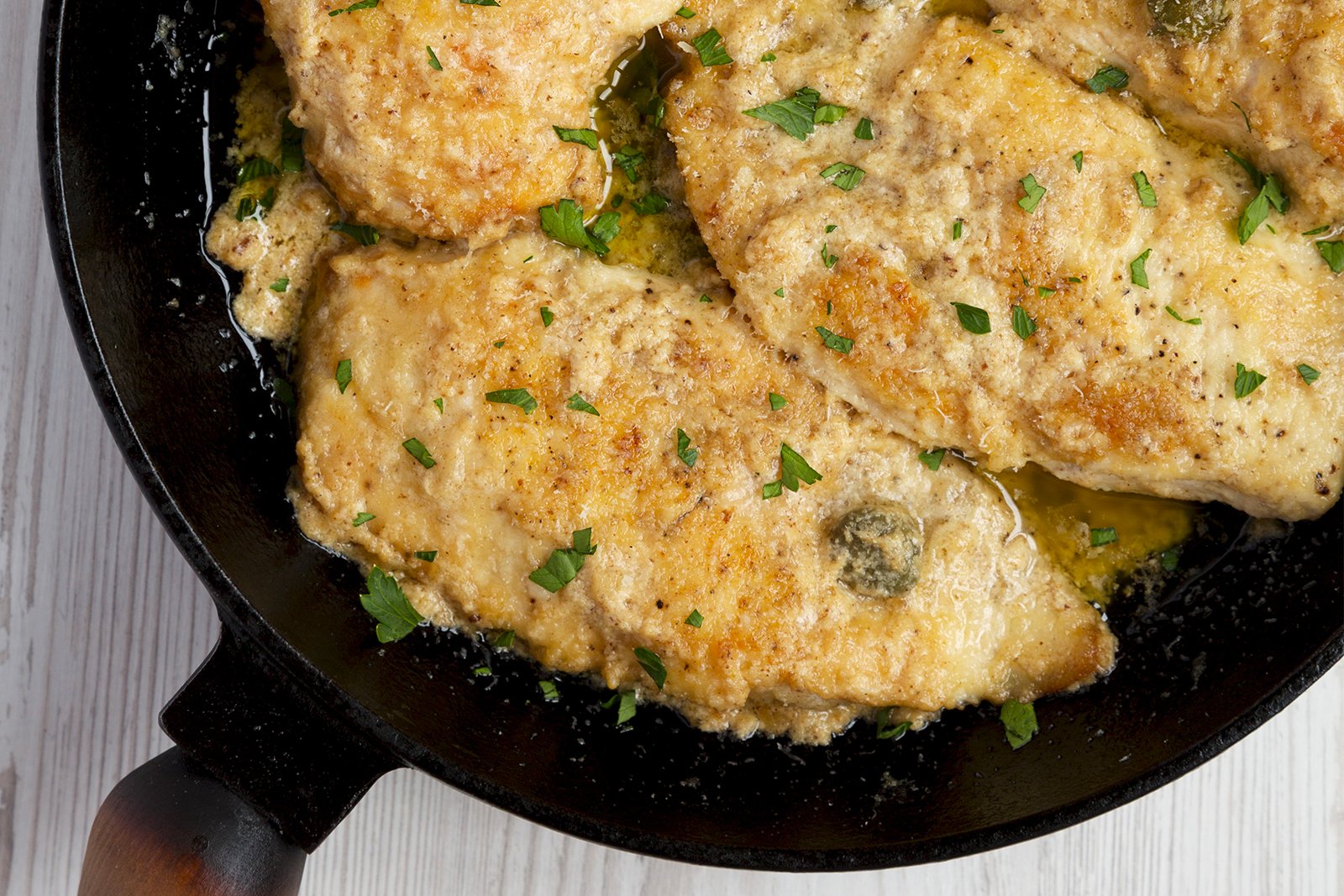 Close-up of chicken piccata in black pan simmering.jpg