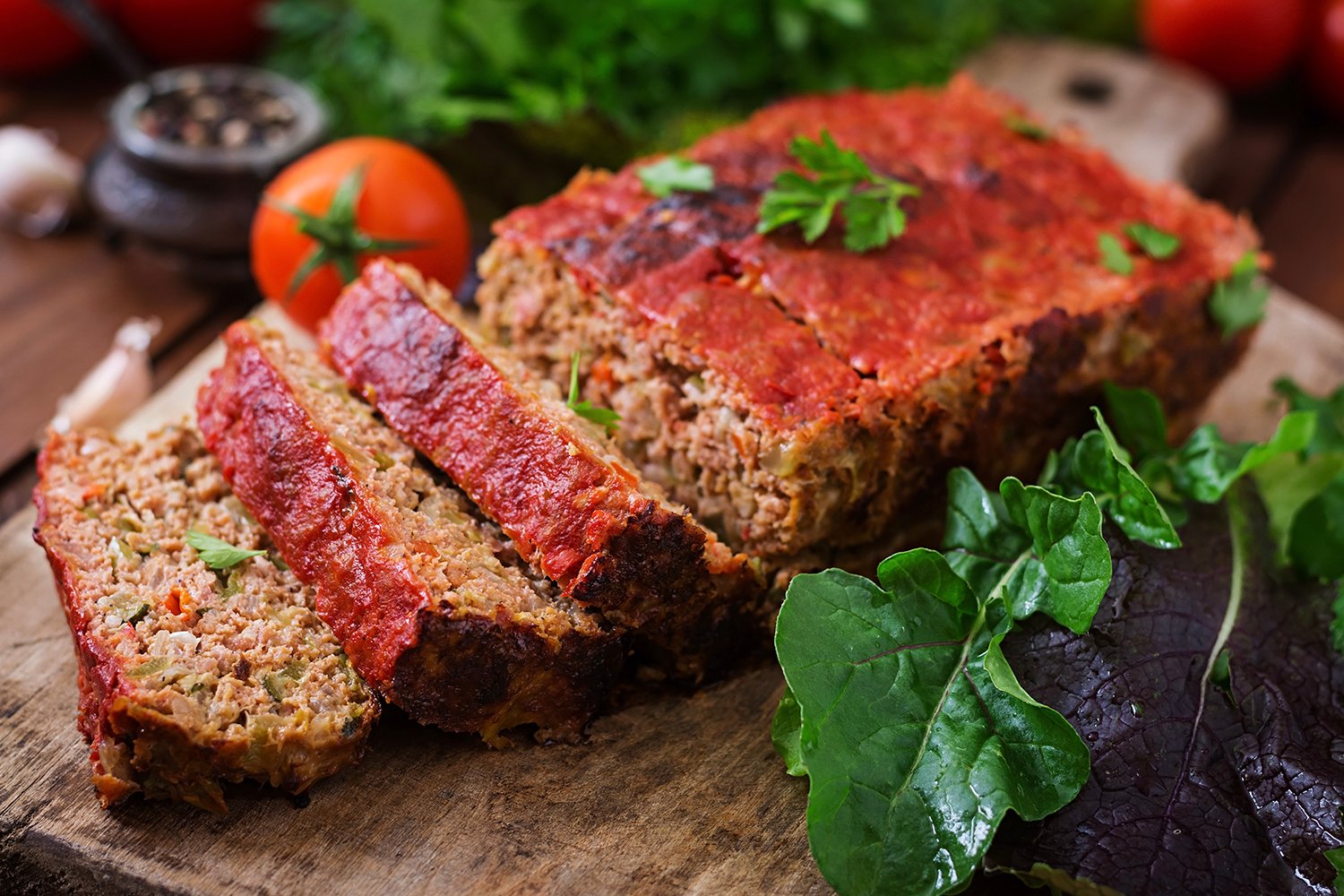 Italian Meatloaf with pasta sauce on top and italian condiments surrounding dish