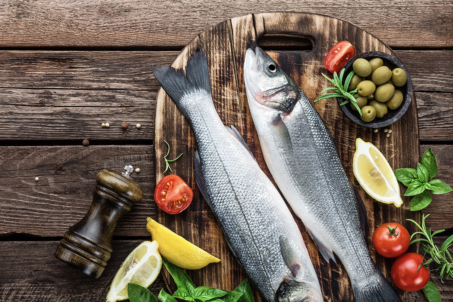 Stovetop Whole Fish on cutting board with olives, tomatoes, and lemons around